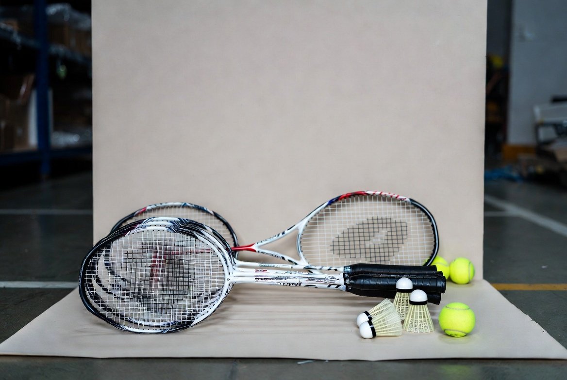 Badminton and tennis rackets with shuttlecocks and balls displayed neatly