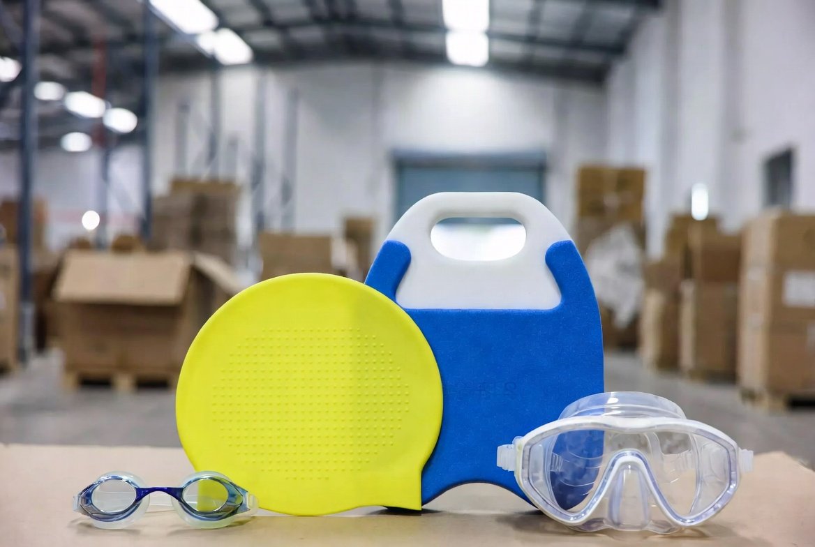 Swimming goggles, swim caps, and kickboards laid out as water sports accessories